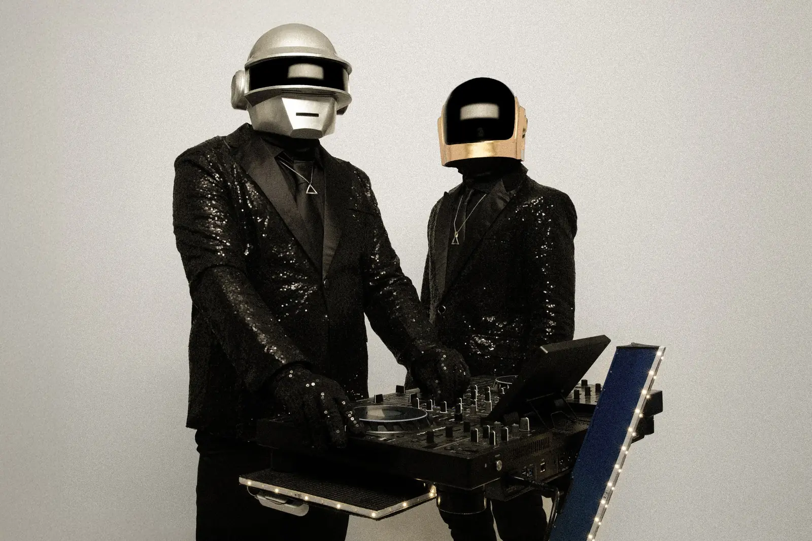 The silver-helmet performer at the DJ console, with the gold-helmet performer alongside