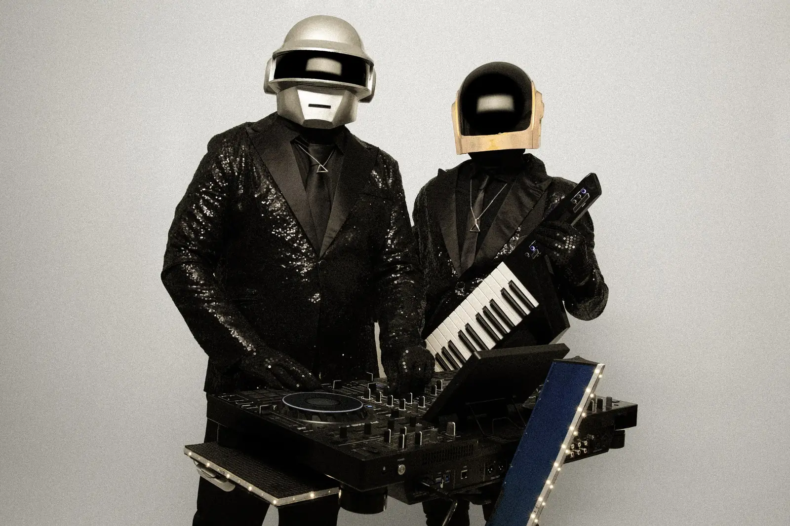 The two INSTANT CRUSHES performers, in silver and gold helmets, at the DJ console and on keytar