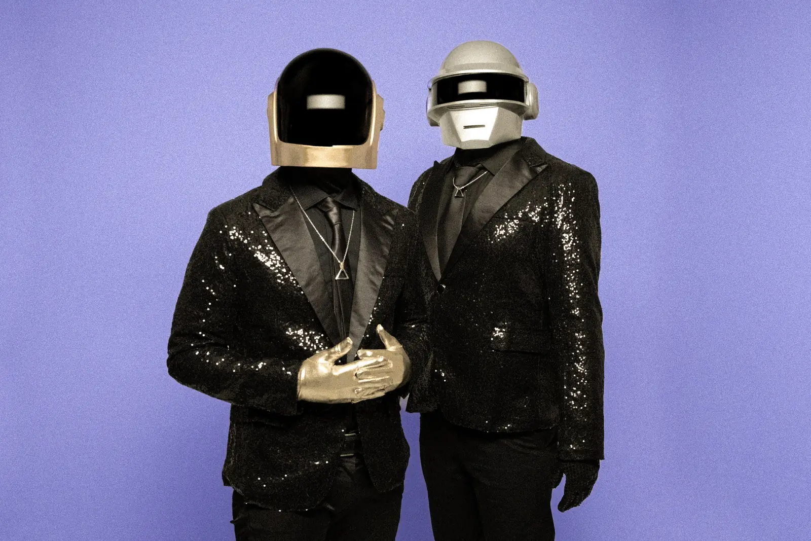 The two performers against a purple backdrop, in black sequin jackets and gold gloves